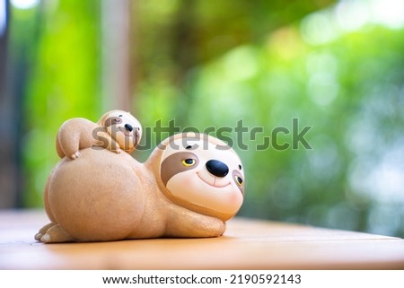 Two slot dolls were placed on a wood table, big one and small one, with bamboos on the background 
