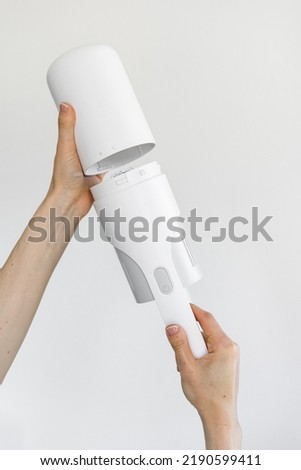 Replacement of the air filter on the portable and cordless vacuum cleaner. Process of changing battery on a electric hoover. Maintenance checking household appliance against white copy space wall Royalty-Free Stock Photo #2190599411