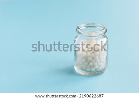 Homeopathic pills and a glass bottle on a blue background. Homeopathic medicine	