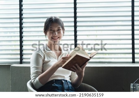 Smiling student girl reading book at coffee shop, education, high school, university, learning and people concept.