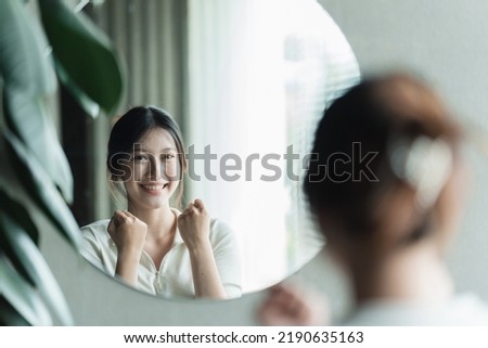A young Asian woman talks to herself through a mirror to build her self-confidence and empower herself. Royalty-Free Stock Photo #2190635163