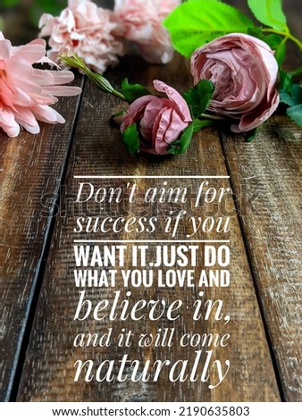 motivational quote about success "Don't aim for success if you want it; just do what you love and believe in, and it will come naturally" on the wooden table with flowers concept