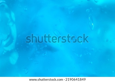 Texture of transparent antiseptic gel with air bubbles on blue background. Summer ocean imitation. Concept of skin moisturizing, prevention of virus. Liquid beauty product closeup. Backdrop, flat