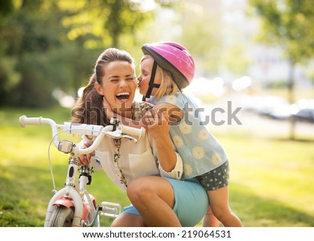 Happy mother and baby girl having fun in park with bicycle Royalty-Free Stock Photo #219064531
