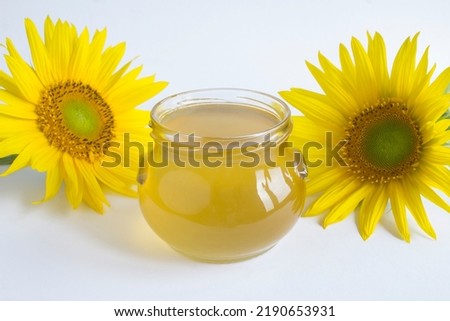 Honey in the glass jar and sunflower on the white background. Close-up.
