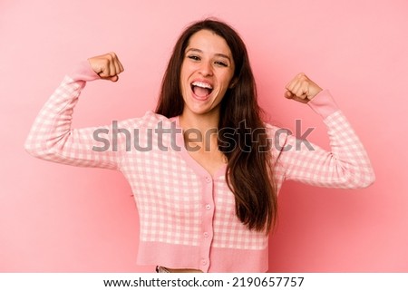 Young caucasian woman isolated on pink background showing strength gesture with arms, symbol of feminine power