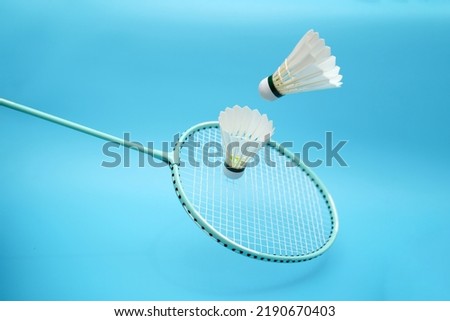 Badminton shuttlecock and badminton racket on blue background Royalty-Free Stock Photo #2190670403