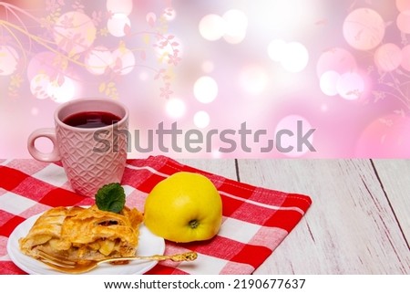 A slice of homemade baked fresh apple strudel with a cup of coffee and a fresh apple on red picnic cloth over abstract spring background. Concept morning coffee. Space.