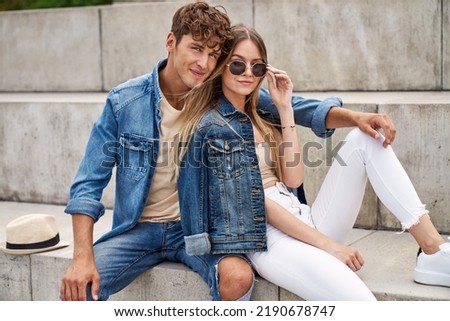 Photo of attractive couple wear denim clothes sitting outdoor and looking at camera Royalty-Free Stock Photo #2190678747