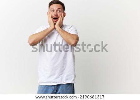 Shocked excited happy tanned handsome man in basic t-shirt touch cheeks open mouth posing isolated on over white studio background. Copy space Banner Mockup. People emotions Lifestyle concept