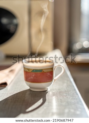Cup of coffee with smoke, morning on background of the window and long shadow on the table