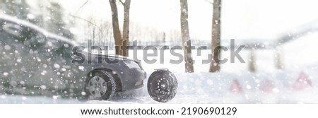 A man near a broken car on a cold winter day
