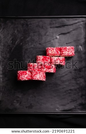 red caviar California sushi roll on black surface flat lay