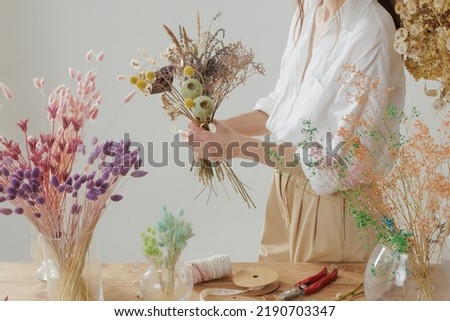 Medium height woman working with dried flowers assemble composition, decor and floristry concept Royalty-Free Stock Photo #2190703347