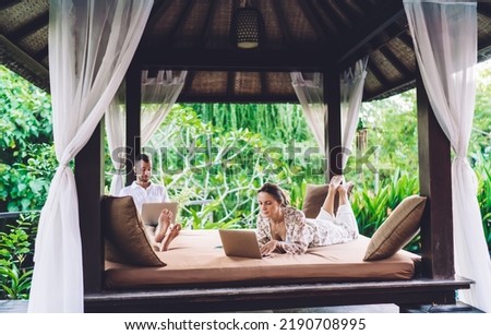 Young male and female using 4g wireless for chatting and messaging via netbook technology during weekend leisure spending at comfortable terrace, skilled marriage browsing social networks
