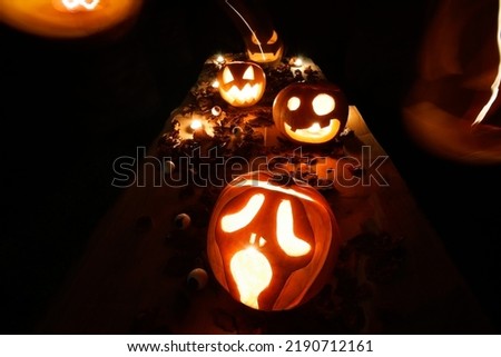 Scary Halloween pumpkins with eyes glowing inside at black background