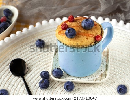 Delicious homemade blueberry muffin mug cake with fresh berries . Cooked in a cup in the microwave. cupcake in a blue mug decorated with blueberries. vanilla mugcake dessert. Easy to cook concept Royalty-Free Stock Photo #2190713849