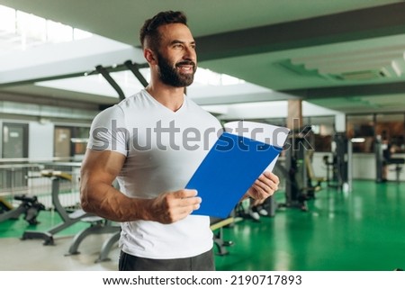Young coach making a training plan in a gym. Copy space
