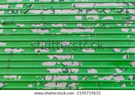 Peeling green paint in messy pattern on corrugated metal surface Royalty-Free Stock Photo #2190719635