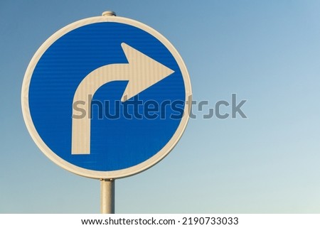 Road sign blue right turn signal on sky background Royalty-Free Stock Photo #2190733033