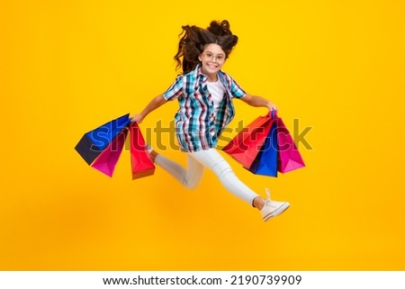 Amazed teen girl. Girl teenager with shopping bags isolated on yellow backgound. Shopping and sale concept. Excited expression, cheerful and glad.