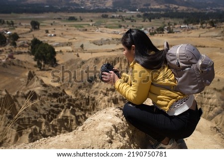 Tourist woman taking pictures with a professional camera on a tourist mountain in South America. Concept of technology, travel, vacation and tourism.