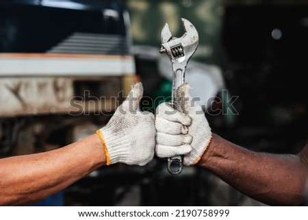Close-up hand mechanic with his tool holding a spanner while at a garage.