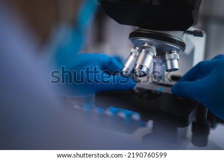 Scientist analyzing microscope slide at laboratory. Young woman technician is examining a histological sample, a biopsy in the laboratory of cancer research Royalty-Free Stock Photo #2190760599