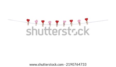 Nine wood clothes clip with red and pink heart shape patterns  hanging on white string line isolated on white background , clipping path