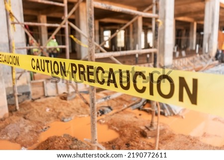 Caution tape with the word caution written in Spanish and English Royalty-Free Stock Photo #2190772611