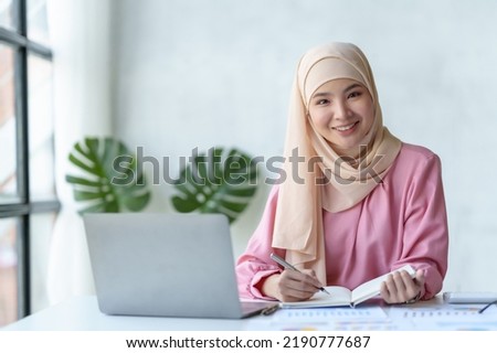 Beautiful muslim Asian businesswoman working on desk with laptop and document received in office.
