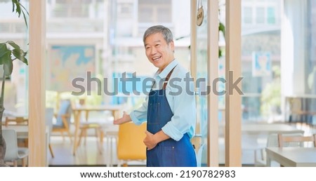 old asian man wecomimg customers at front door in cafe or restaurant