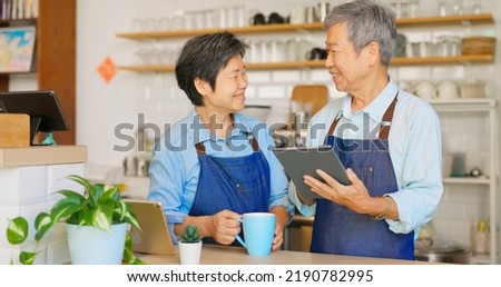 old asian man use the tablet to see income status or content of guests order and old asian woman brings him a cup drink Royalty-Free Stock Photo #2190782995