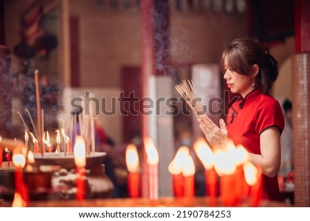 An Asian woman lighting incense sticks to pay homage to the Chinese New Year. Royalty-Free Stock Photo #2190784253