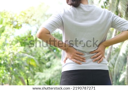 Woman's hand She is caught at the waist and her back is painful at the back in the park. Cause of the exercise. Royalty-Free Stock Photo #2190787271