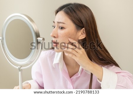Dermatology, expression face worry asian young woman looking mirror hand touch facial at dark spot of melasma, freckles from pigment melanin, allergy sun. Beauty care, skin problem treatment, skincare Royalty-Free Stock Photo #2190788133