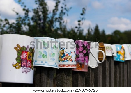 Old cups on the slats of an old fence. Traditional folk ornament. South Moravia, Czech Republic.