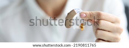 Hearing aid to improve hearing in female hands. Choosing a hearing aid concept Royalty-Free Stock Photo #2190811765