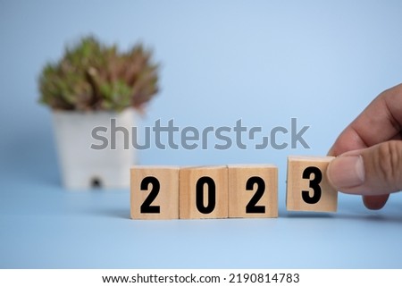 Hand man holding wood cube block 2023 on background.