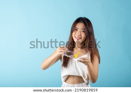 Facial Beauty Treatment Hygiene Skin. Happy Asian beautiful young woman drop removing cosmetic make up water to pad cotton face cleaner disc for cleaning, studio shot isolated on blue background
