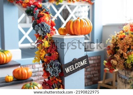 Residential house decorated for Halloween holiday. Different colored pumpkins in front door On Wooden Steps. Porch of yard decorated with orange pumpkins in autumn. Thanksgiving. Halloween outside.