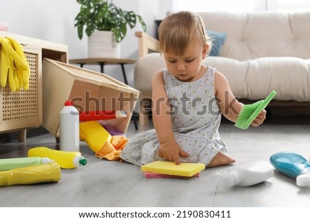 Cute baby playing with cleaning supplies on floor at home. Dangerous situation Royalty-Free Stock Photo #2190830411