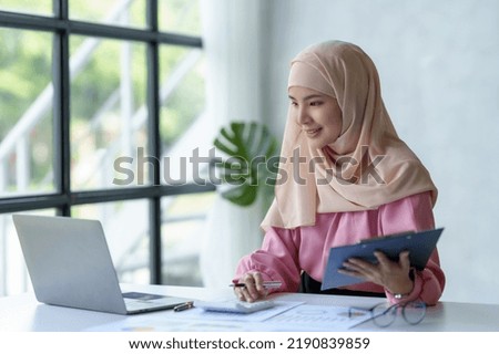Beautiful muslim Asian businesswoman working on desk with laptop and document received in office