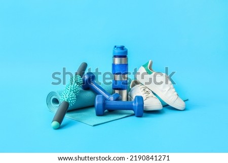 Set of sports equipment, shoes and bottle of water on color background