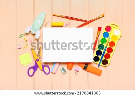 Blank paper sheet with rocket and school stationery on color wooden background