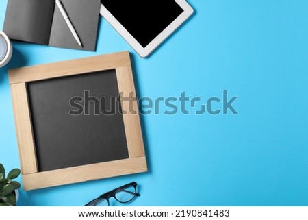 Flat lay composition with small chalkboard on light blue background, space for text