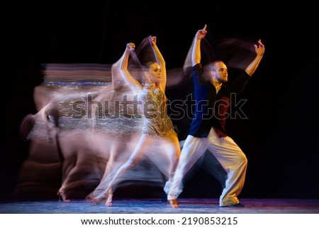 Freedom. Two professional dancers dancing ballroom dance isolated on dark background with mixed light. Concept of art, dance, beauty, music, style. International Dance Day