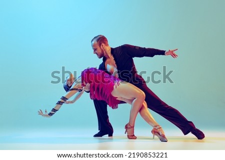 Emotions. Beautiful woman and man, professional dancers dancing ballroom dance isolated on blue background. Concept of art, dance, beauty, music, style. Copy space for ad. International Dance Day