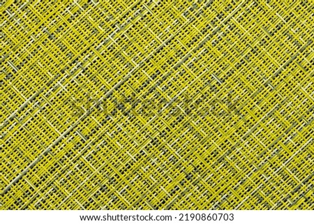 A fragment of a straw rug, as a background or texture, yellow and gray color, close-up.