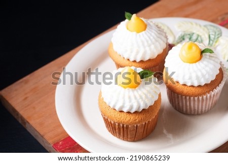 Food concept Homemade organic Lemon Meringue Cupcakes on wooden board and black background with copy space